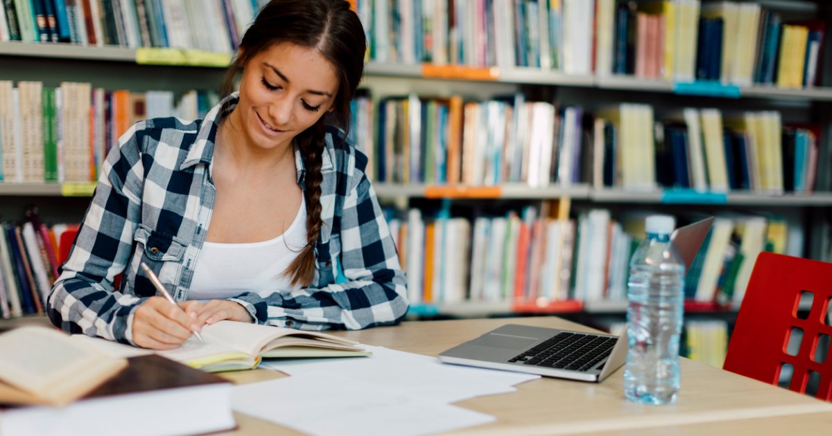 Female student using laptop for taking notes to study.